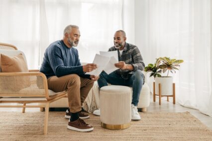 Two men talking, looking at documents.