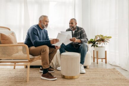 Two men talking, looking at documents.