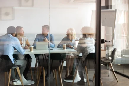 A group of 5 people working around a desk