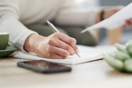 Closeup shot of an unrecognisable businesswoman writing notes while going through paperwork in an office