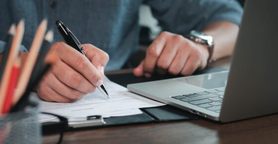 Close-up of man hand using writing pen memo on notebook paper or letter, diary on table desk office.