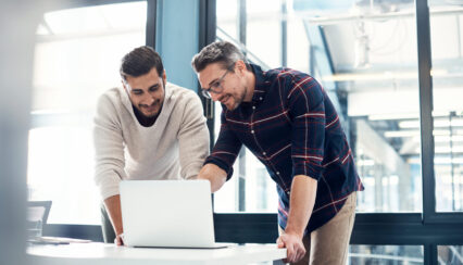 Two businessmen working together on a laptop in an office