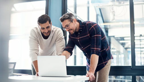 Two businessmen working together on a laptop in an office