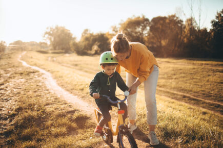 Mum helping her son ride a bike.