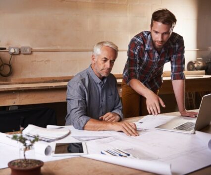 Two men talking at a desk.